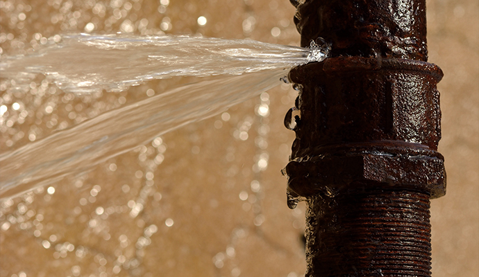 A burst rusty pipe is leaking water