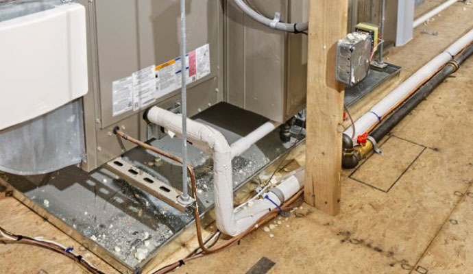 A metal emergency drain pan underneath an HVAC unit