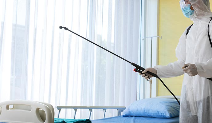A person disinfecting a bed in hospital