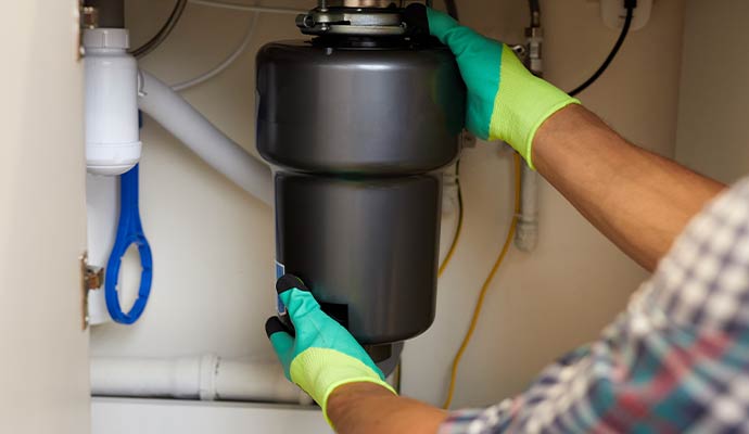 A professional of Panhandle Cleaning & Restoration installing garbage disposal unit
