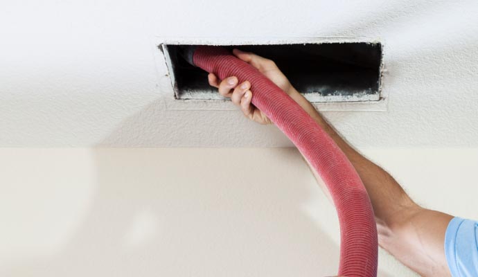 Person cleaning air duct with equipment