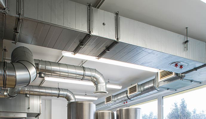 Air ducts and ventilation piping installed on a bright office ceiling