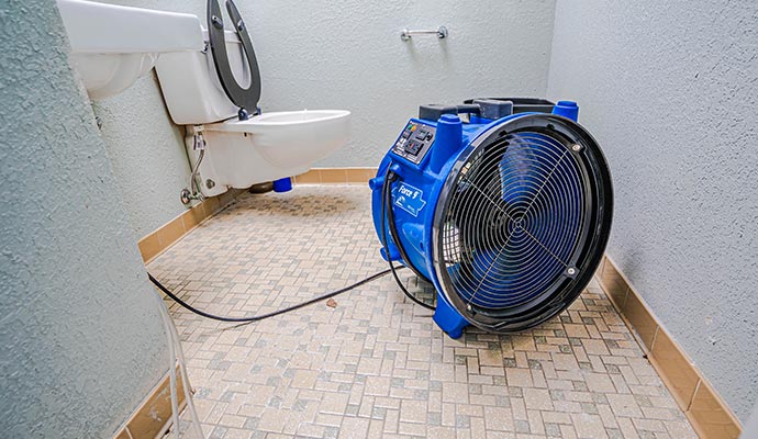 Air mover drying a bathroom floor after sewage backup.