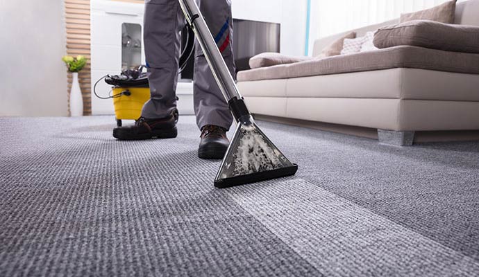 Person cleaning carpet with equipment