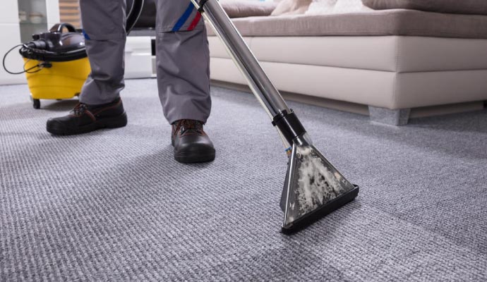 Person cleaning carpet with equipment