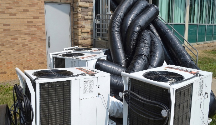 Multiple portable industrial air conditioning units connected to flexible ducting tubes