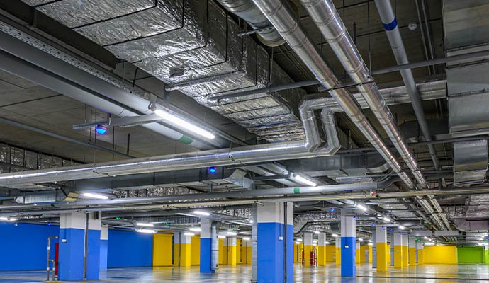 Complex industrial duct network installed across a parking garage ceiling