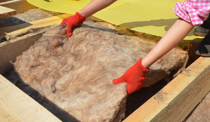 Expert is removing fibrous insulation from a wooden frame