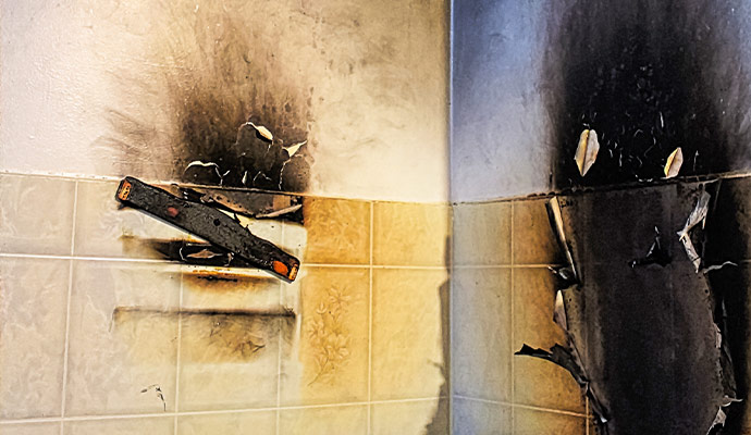 Interior tiled wall charred and blackened by fire and heavy soot