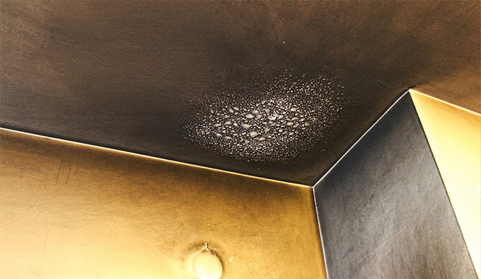 Heavy soot and smoke residue accumulation on a room ceiling and wall corner