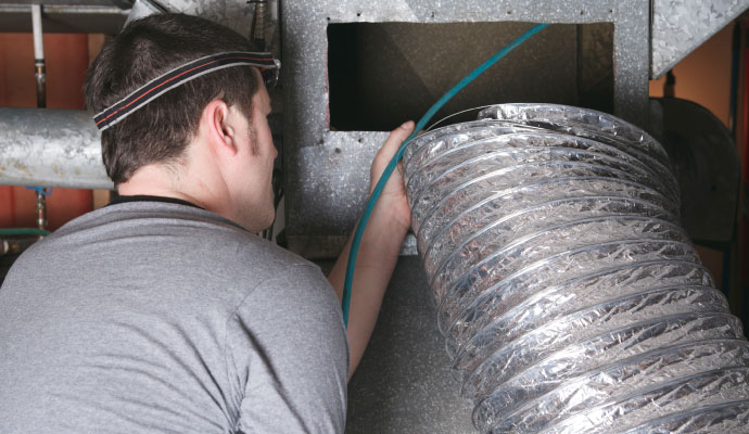 Technician cleaning and removing smoke soot from flexible HVAC air ductwork
