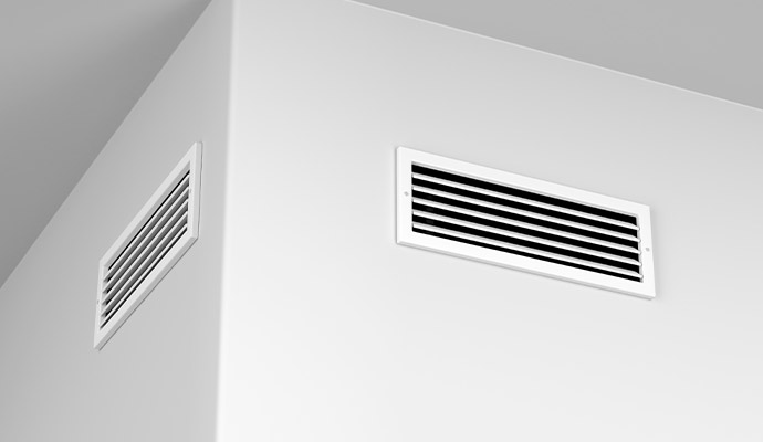 Two rectangular white metal air vents installed on the wall