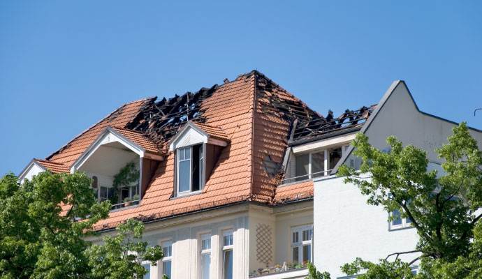 Fire damaged tiled roof with charred rafters