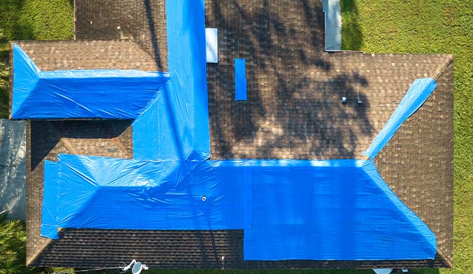 Properly installed blue tarps covering to a damaged residential roof