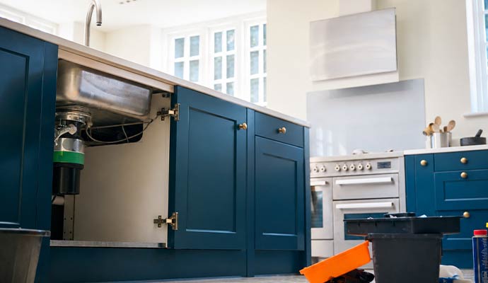 Open kitchen cabinet door showing a garbage disposal unit