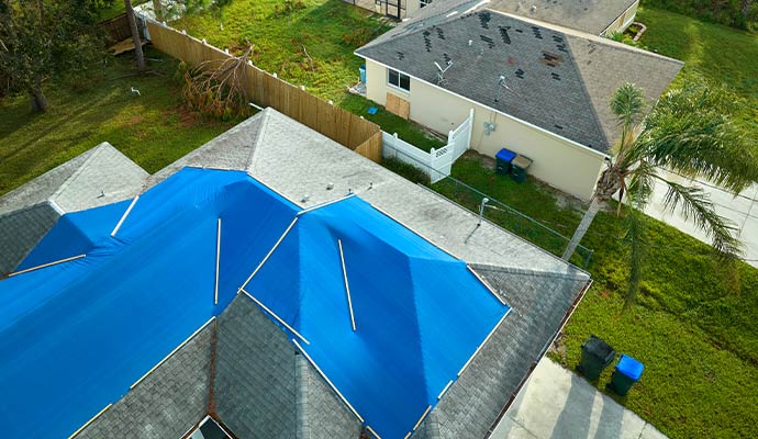 Residential roof covered with blue tarp