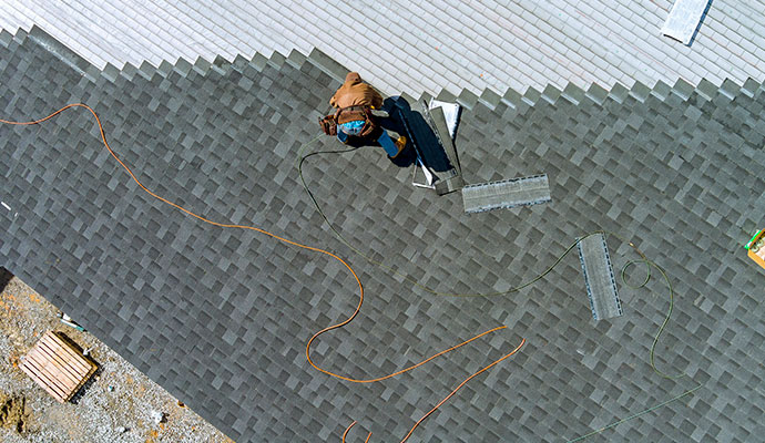 Overhead view of a professional roofer installing new shingles on a residential roof