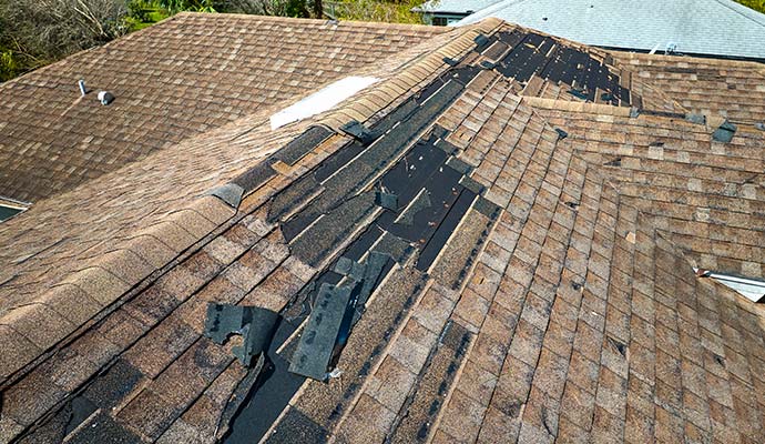 Wind damaged roof with missing shingles