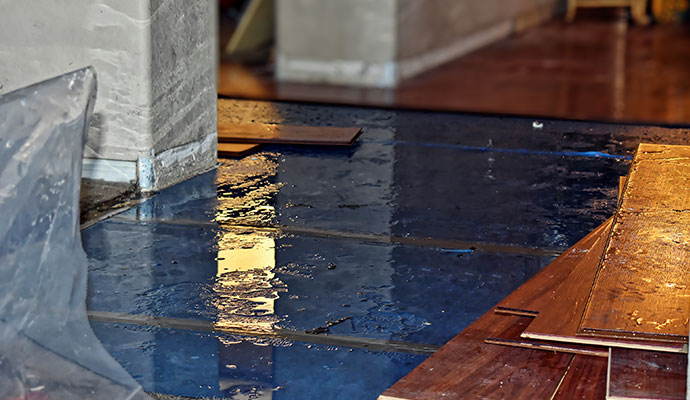 Water damaged floor with standing water and removed boards