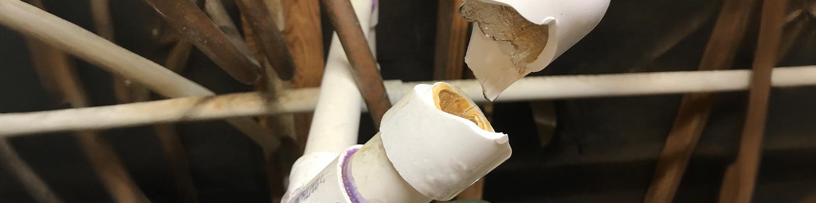 Close-up of a burst white plastic water pipe.