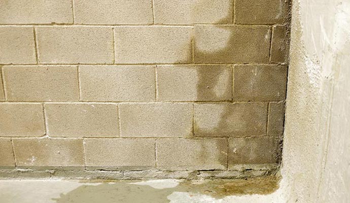 Water stains and seepage on a concrete block basement wall.