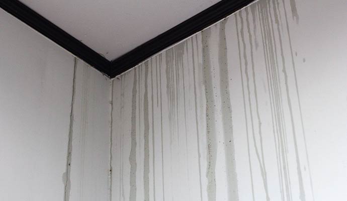 Water running down a white interior wall from the ceiling